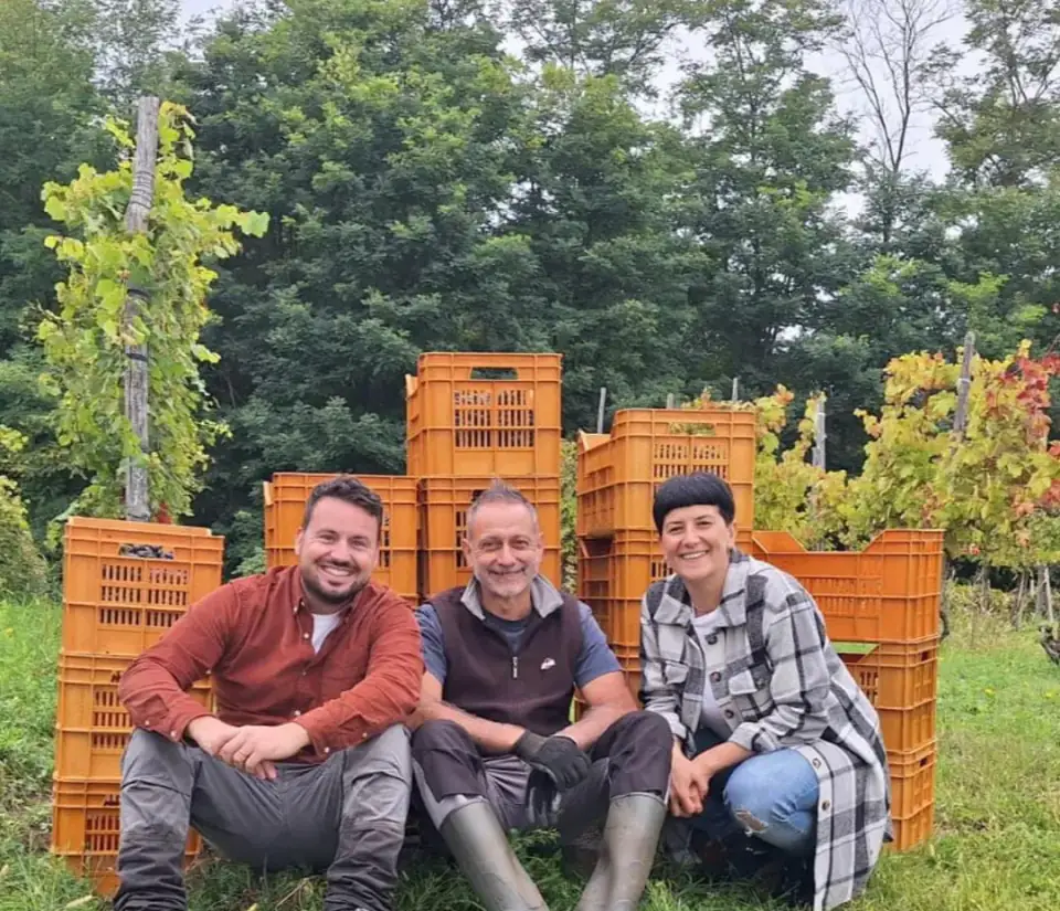 Pietro, Gianni e Valentina seduti davanti alle cassette della vendemmia